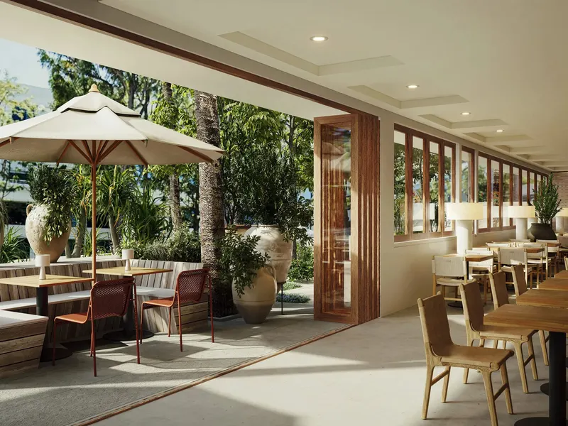 A restaurant terrace with an umbrella table, opening onto an indoor dining room