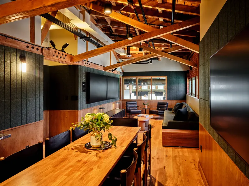 A private dining room with a long timber table under exposed timber trusses