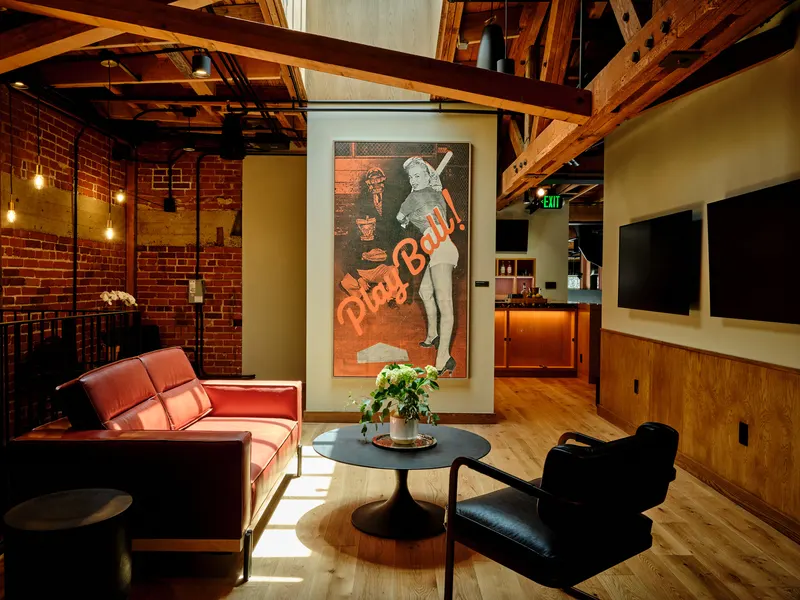 A lounge with a red sofa, brick walls and a framed baseball poster