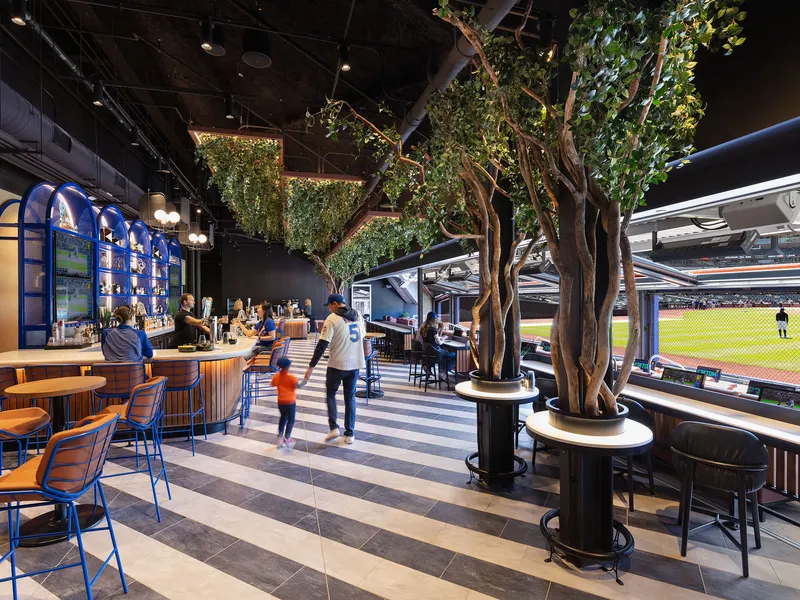 A stadium club lounge with trees planted through the bar tables