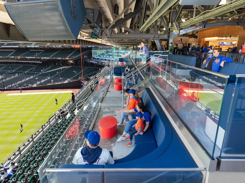 Stadium club seats with blue banquettes overlooking a baseball field