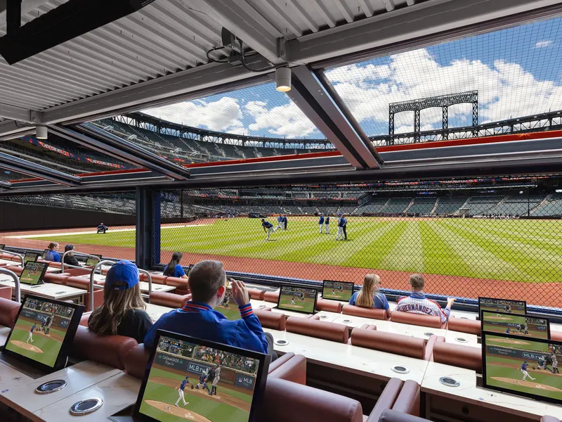 Stadium club seats with tabletop screens overlooking a baseball field