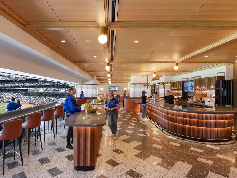 A curved bar in a stadium club lounge with a wood ceiling and a terrazzo floor