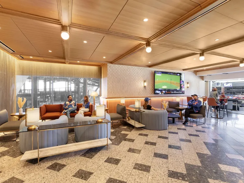 A stadium club lounge with sofas, a timber ceiling and a view to the field