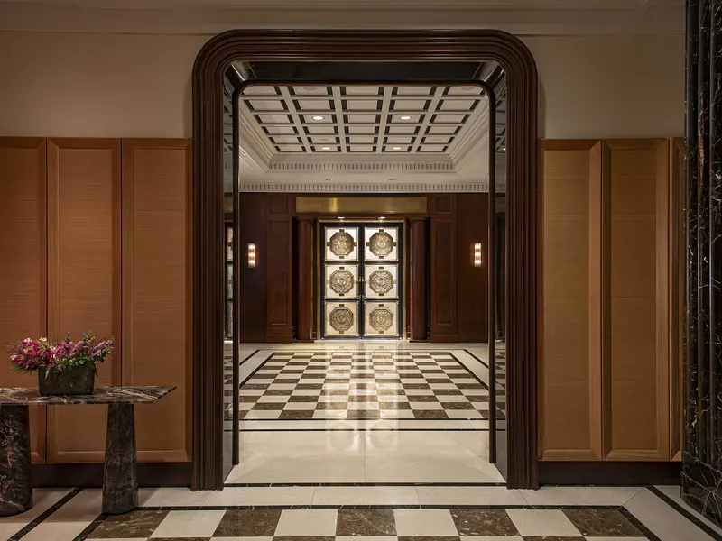 A hotel lobby with a checkered marble floor, seen through a dark stone portal