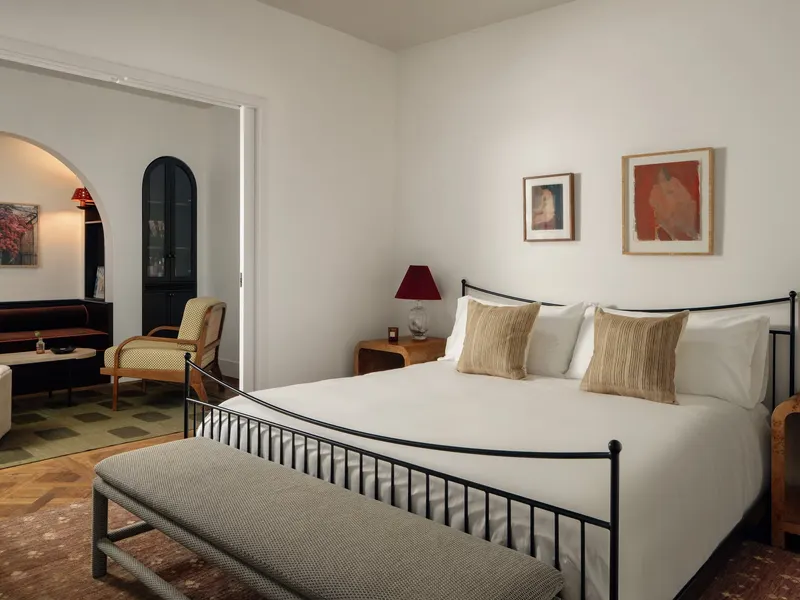 A hotel suite bedroom opening through an arch to a sitting room