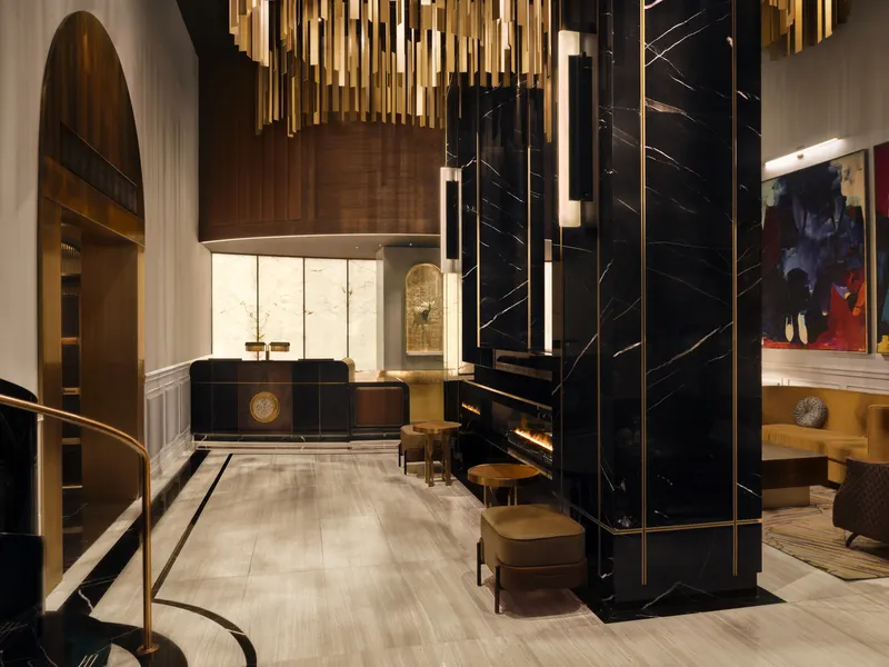 A hotel lobby with a black marble column, brass ceiling rods and a seating area