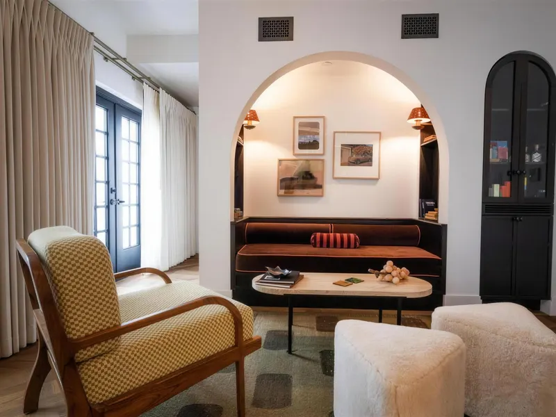 A hotel suite lounge with armchairs and an arched alcove holding a built-in sofa