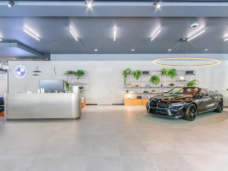 A car showroom with a curved metal reception desk and a convertible on display