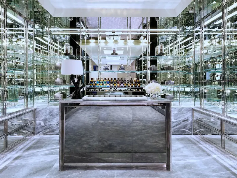 A mirrored store interior with a gray marble counter and glass shelving