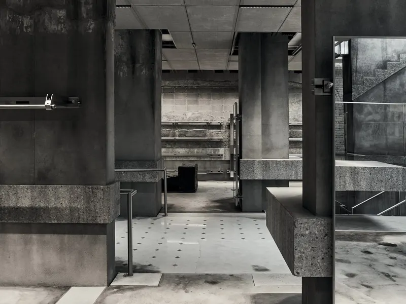 A concrete store interior with dark stone display plinths