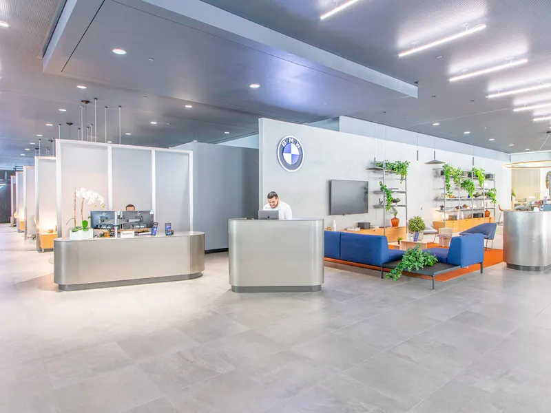 A showroom with service desks, blue seating and planted shelves