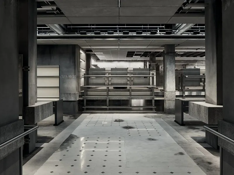 A dark concrete store interior with steel racks and a gray terrazzo floor
