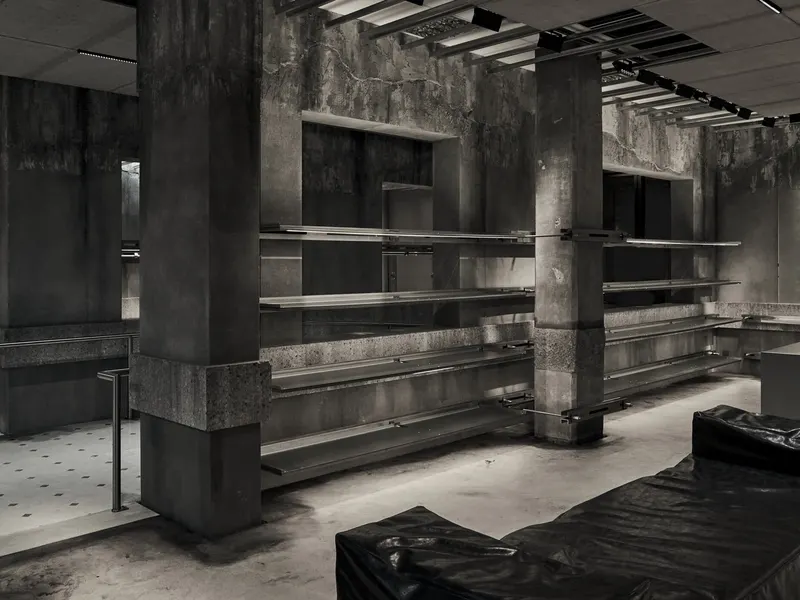 A black and white view of a concrete store with steel shelving between columns