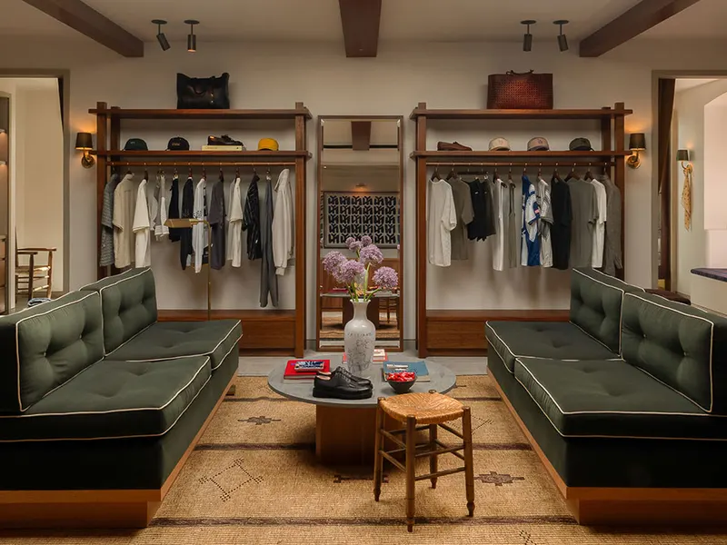 A boutique with green tufted banquettes and timber clothing racks