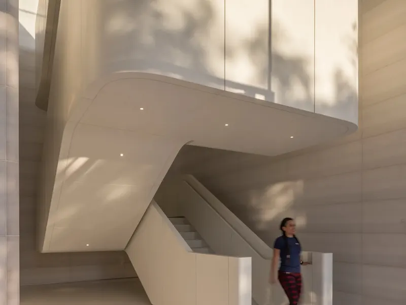 A curved white stair seen from below, with a person walking down