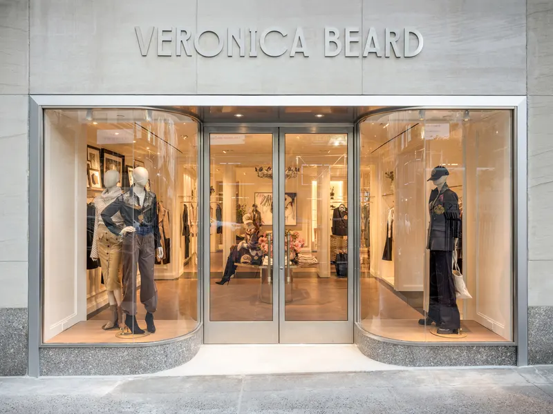 A stone storefront with curved glass display windows and mannequins