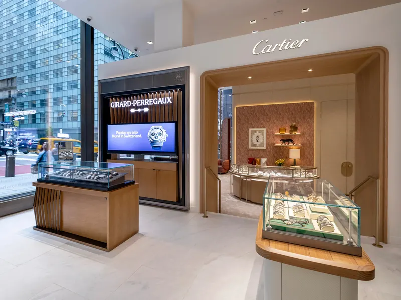 A watch boutique with display cases, a lit screen and a timber-framed niche