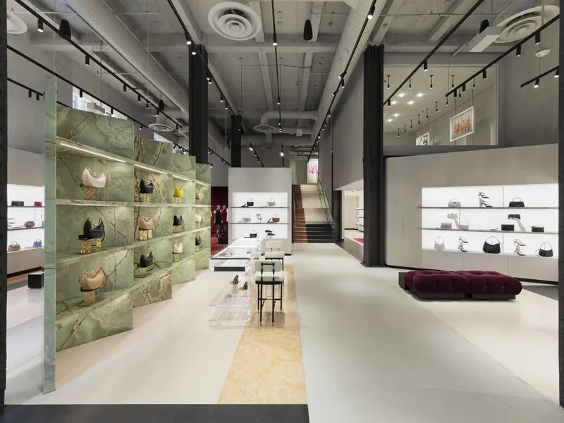 A store with green onyx display walls and lit handbag shelving