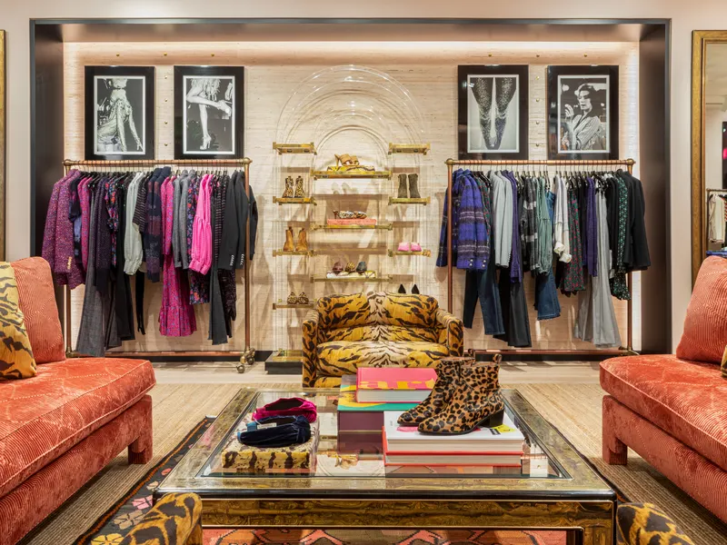 A boutique lounge with orange sofas, framed photographs and racks of clothing
