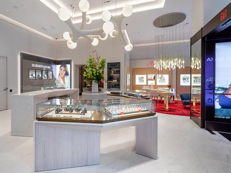 A jewelry store with white stone display cases under a sculptural chandelier