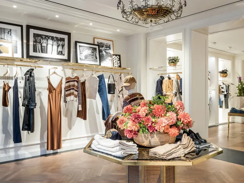 A boutique with framed photographs over clothing racks and a flower display