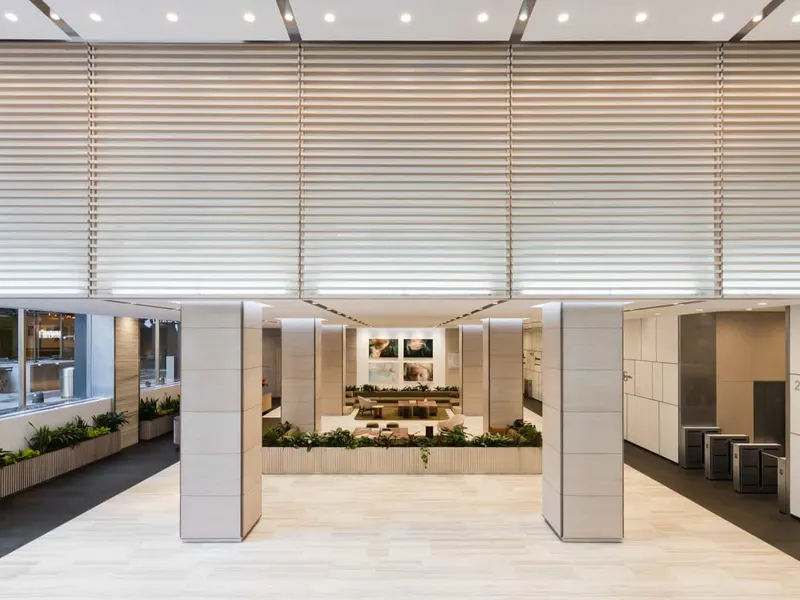 A lobby with stone-clad columns, a planted bed and blinds over the windows