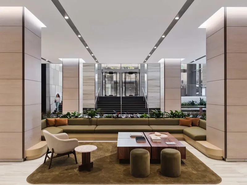 A building lobby with a sunken lounge, stone columns and a stair to the entrance