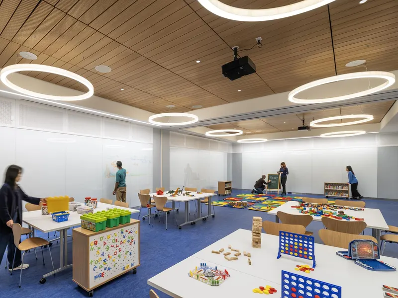 A children's activity room with circular ceiling lights and tables of games