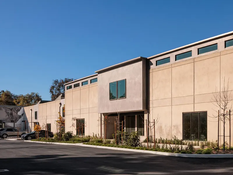 A new two-story stucco building beside a street at dusk, with fresh landscaping
