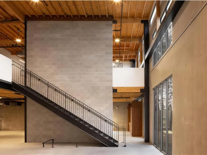 A block-walled interior with a steel stair under an exposed timber roof