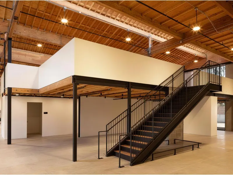 A steel mezzanine and stair inside a building with exposed timber roof framing