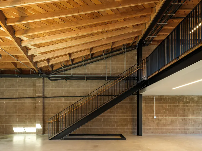 A steel stair along a block wall under exposed timber roof trusses