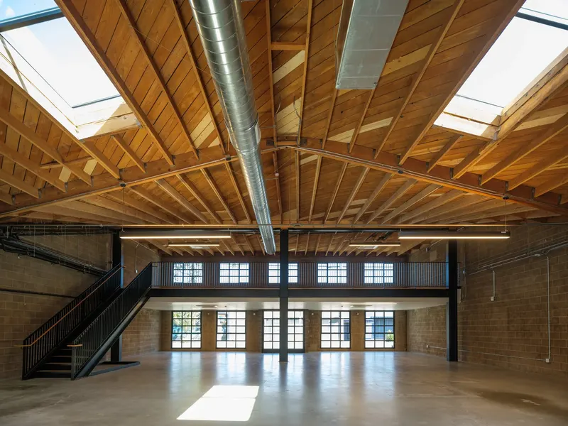 A large open interior under a timber bow truss roof with skylights and a steel mezzanine