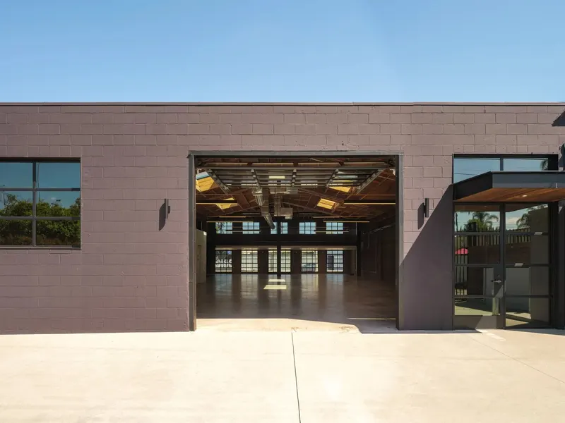 A block building with a wide opening onto a timber-roofed interior
