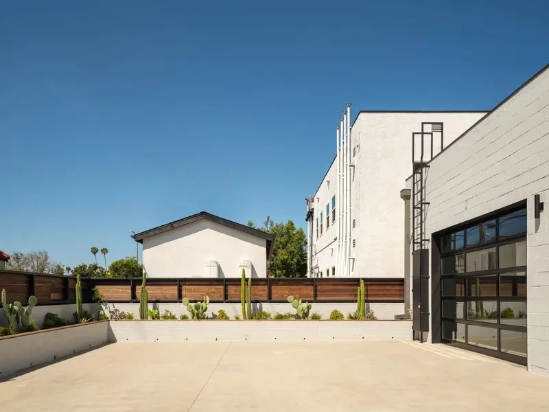 A paved courtyard with block walls, planters and a glass roll-up door