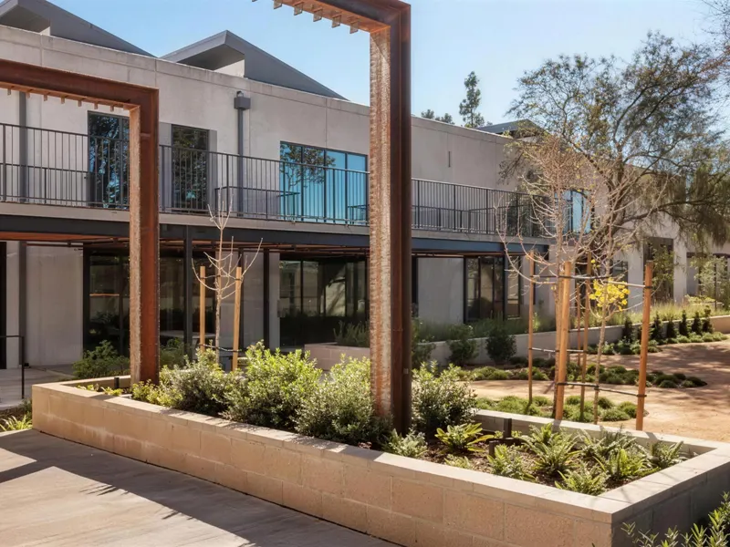 A courtyard with steel portal frames, planters and a two-story office building
