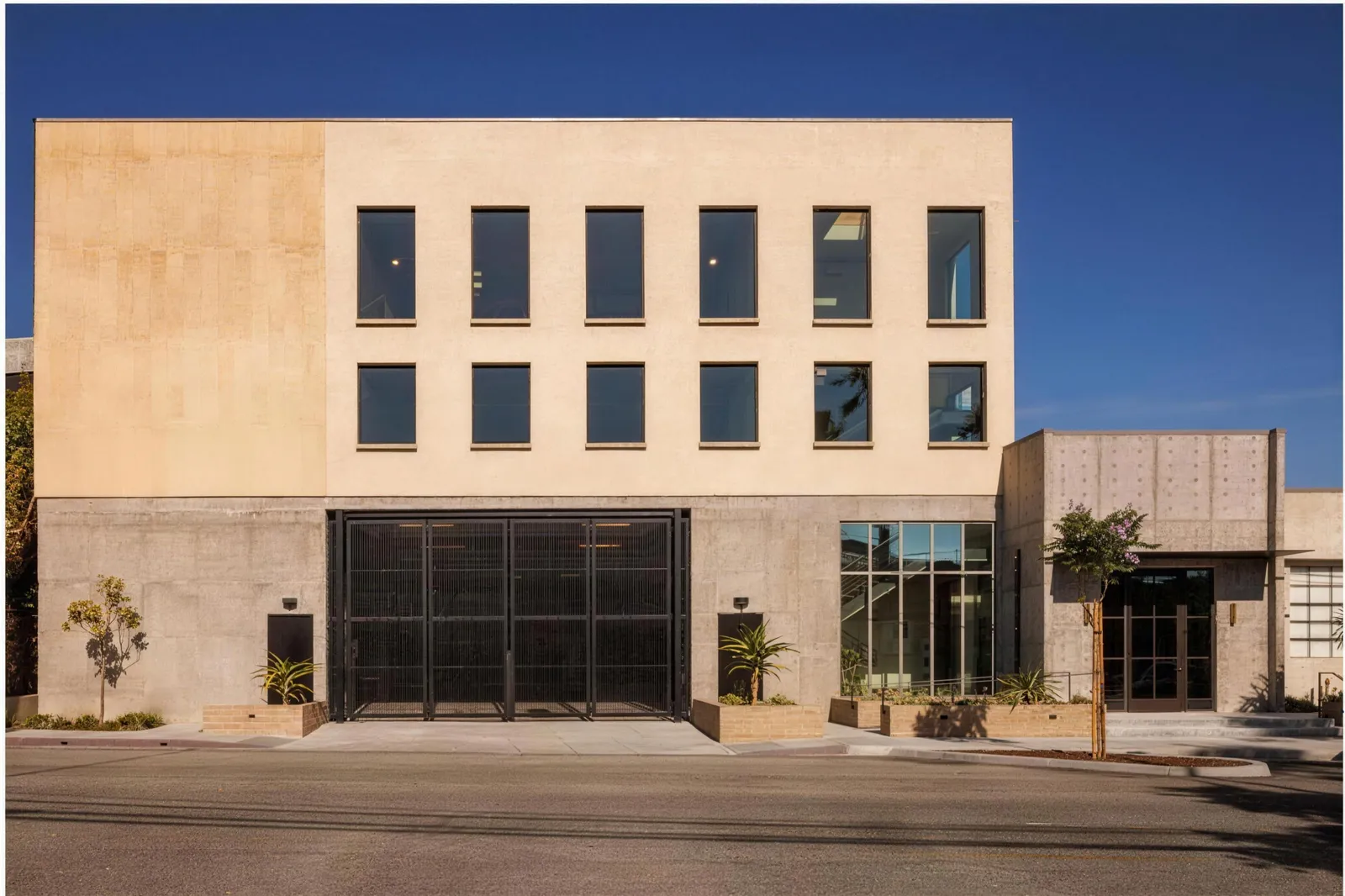 A three storey office building in board-formed concrete with a glazed ground floor