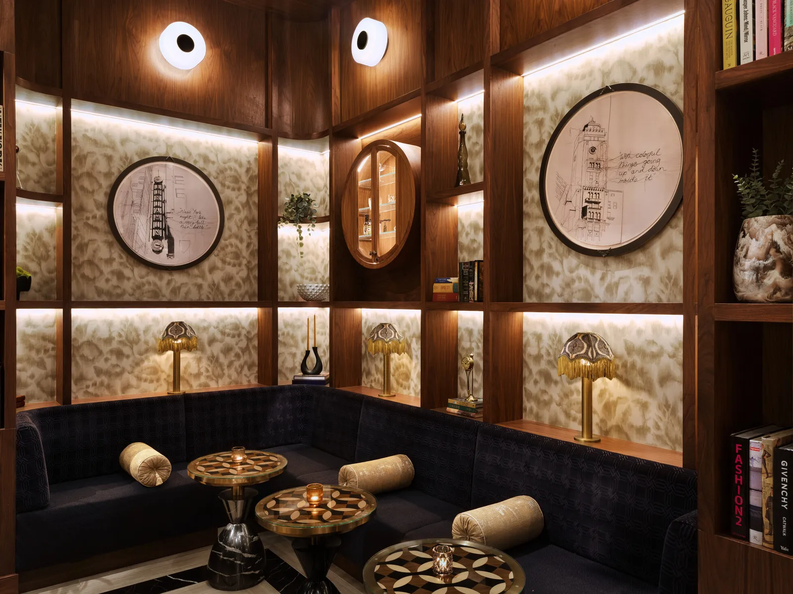 A hotel lounge with lit shelving and patterned wallpaper