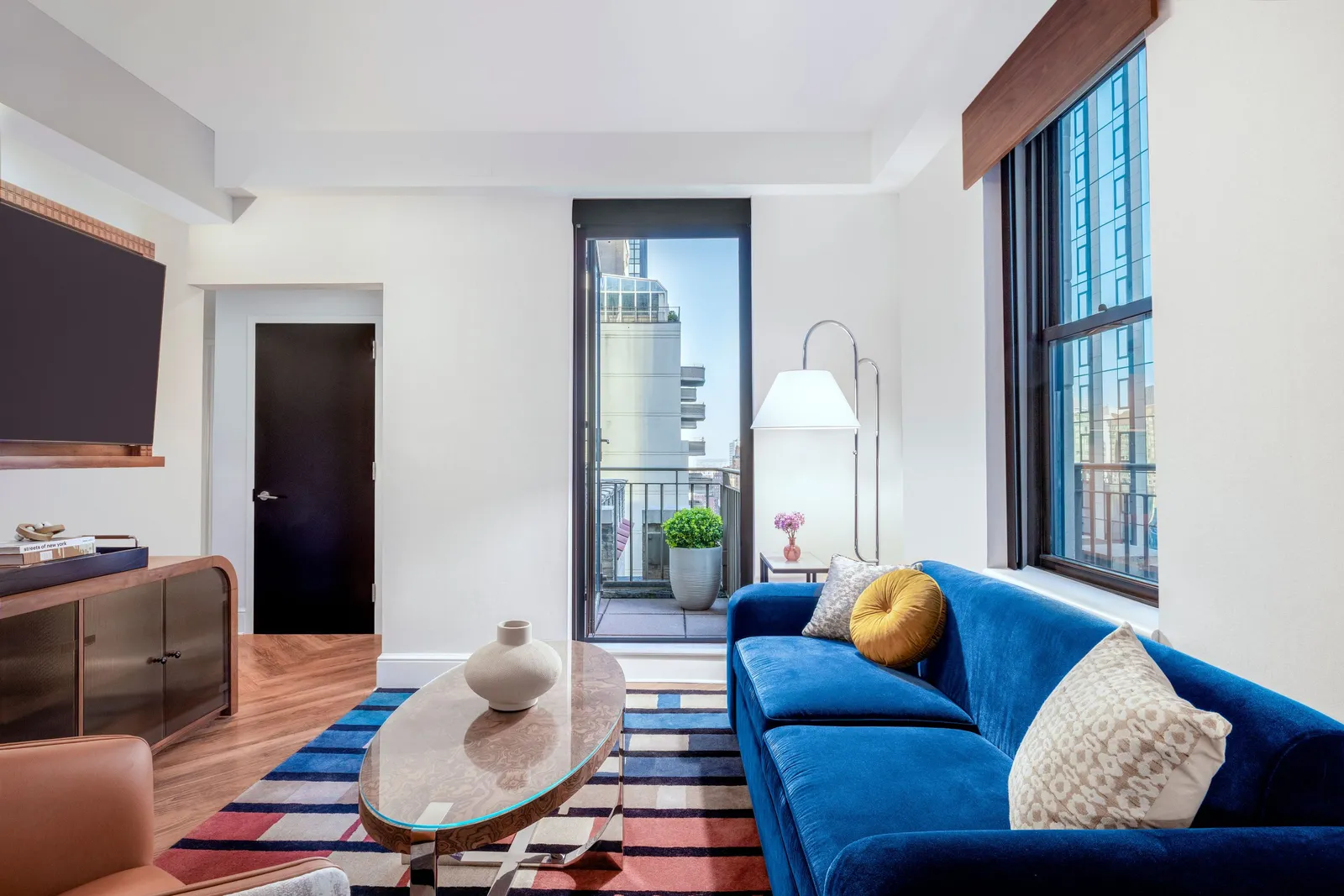 A hotel suite living area with a blue sofa and a door to a balcony