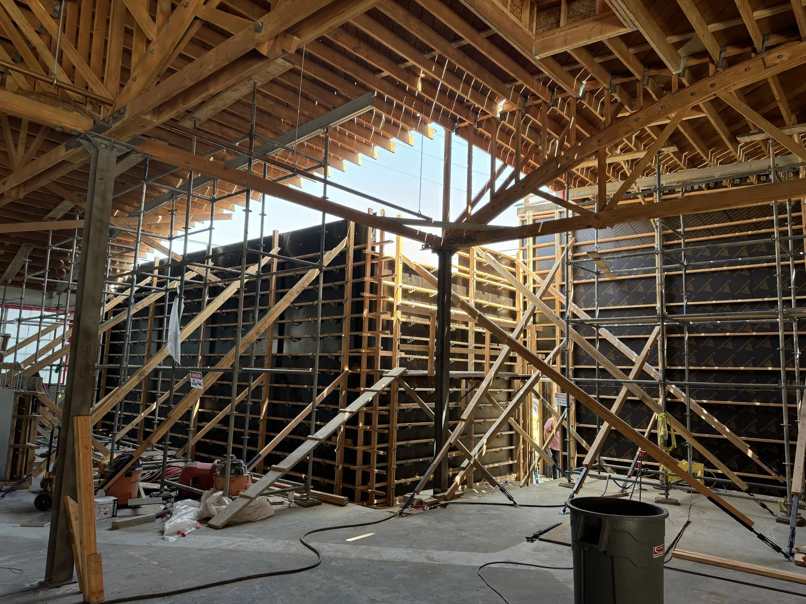 Concrete wall formwork and scaffolding rising under an exposed timber bow truss roof
