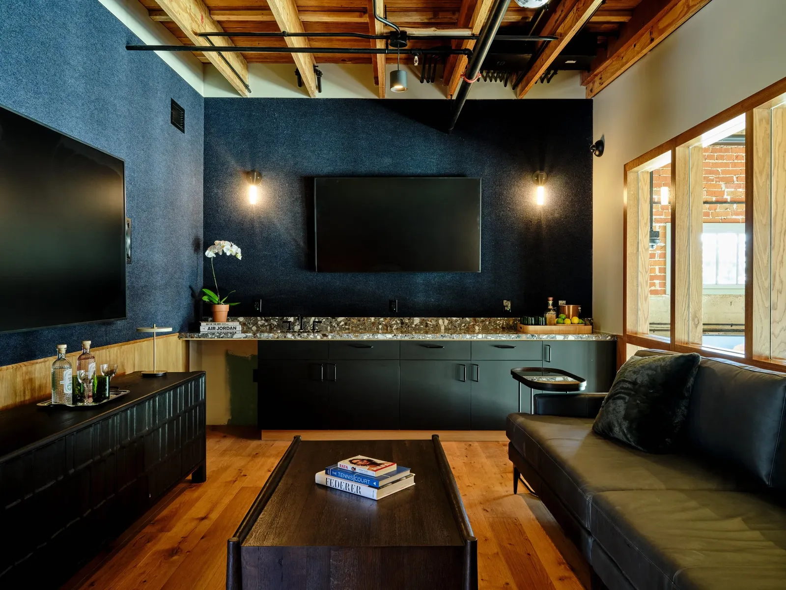 A private lounge with blue felt walls, a terrazzo counter and exposed timber joists