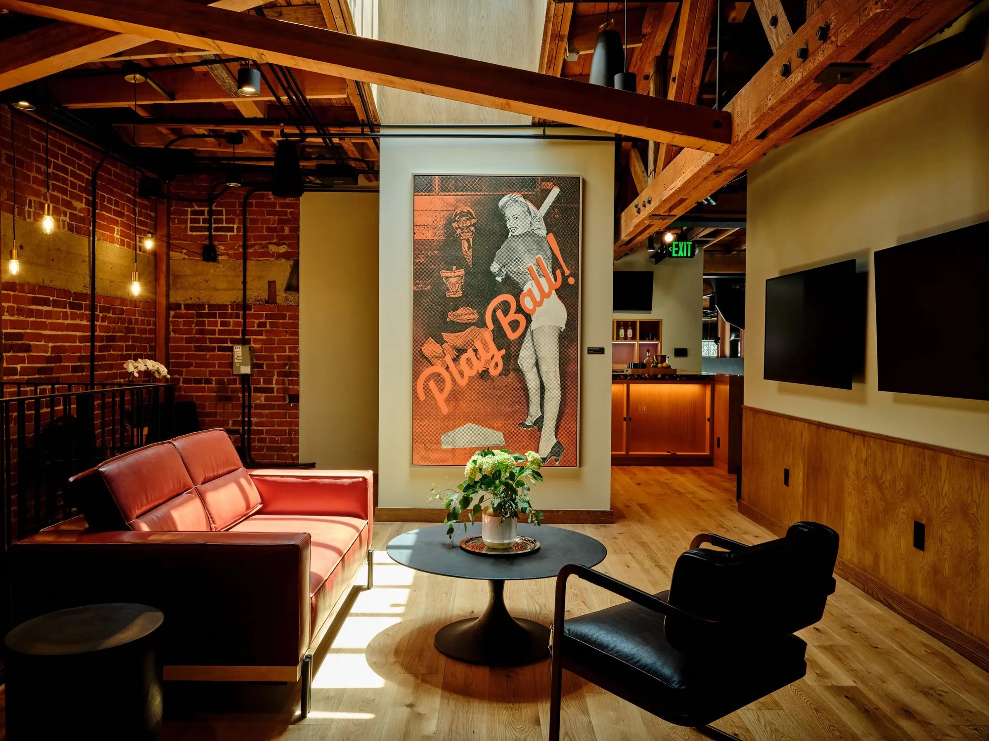 A lounge with a red sofa under a timber ceiling in a 1929 building