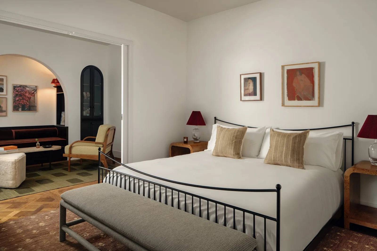A hotel suite bedroom opening through an arch to a sitting room